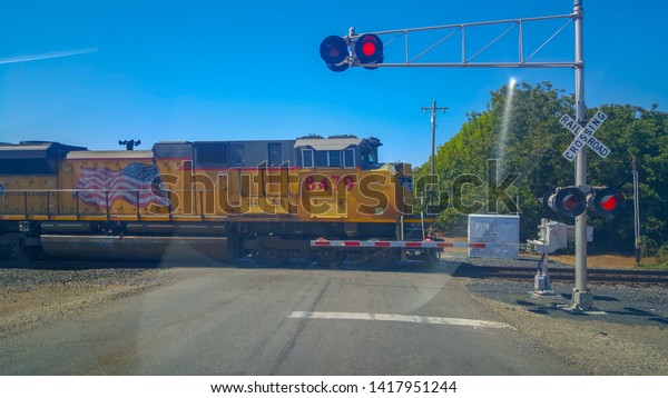 Chico, United States - September 18, 2015 : An\
AMTRAK cargo train is passing a rail crossing between Chico and\
Sacramento