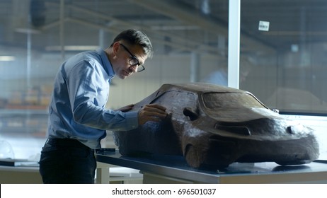 Chief Automotive Designer With Rake Sculpts Futuristic  Car Model From Plasticine Clay. He Works In A Special Studio Located In A Large Car Factory.