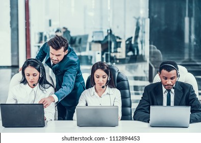 Chief in call center behind multiracial employees with laptops and headsets and supervises their. Work in office. - Powered by Shutterstock