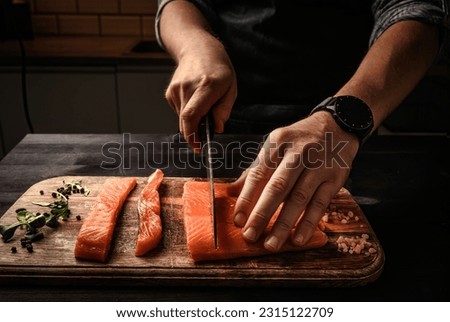 Chief cutting salmon red fish fillet on a cutting board in the kitchen cooking healthy dinner
