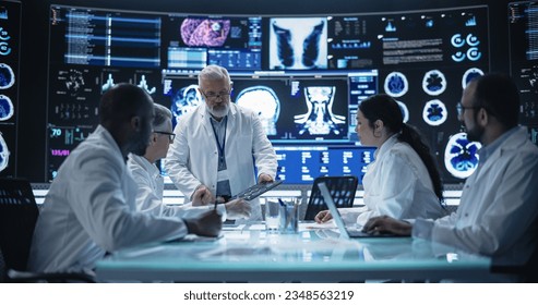 Chief Doctor Conducting a Pre-Operative Assessment Meeting With His Surgical Team. Group of Brain Surgeons Discussing Possible Treatment in an Advanced Laboratory with Interactive Digital Screens - Powered by Shutterstock