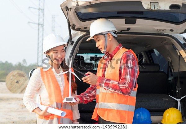 Chief Engineer is man Holding wind turbines \
Explains to a Brilliant Young engineer woman How Wind Turbines\
Work.  Engineer woman Learning about Eco-Friendly Forms of\
Renewable Energy.