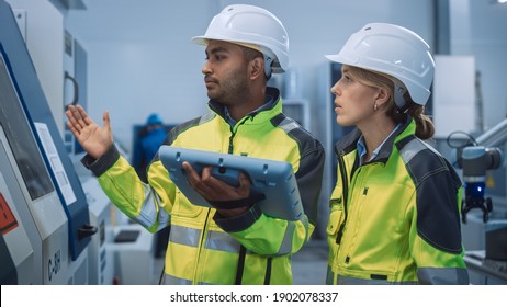 Chief Engineer And Project Manager Wearing Safety Vests And Hard Hats, Use Digital Tablet Controller In Modern Factory, Talking, Optimizing CNC Machinery, Increasing Production Line Efficiency