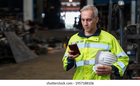 The chief engineer is using his phone and drinking coffee during the break. Lazy workers stop working and play on their phones, chats or social media. During work time at factory in worker concept - Shutterstock ID 1957188106