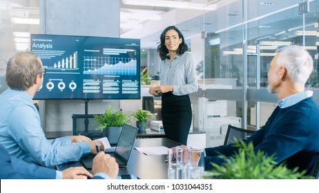 Chief Female Executive Gives a Report/ Presentation to Her Colleagues in the Meeting Room, She Shows Graphics, Pie Charts and Company's Growth on the Wall TV. - Shutterstock ID 1031044351