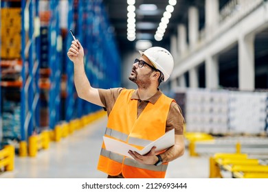A chief with folder counting boxes in warehouse.