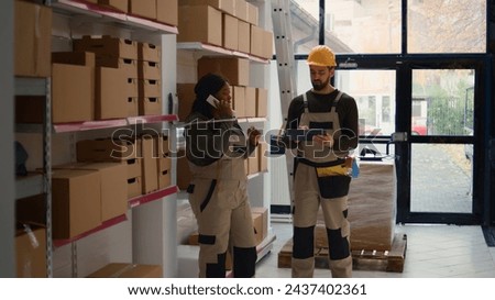 Chief logistics officer and employee preparing warehouse orders for delivery, using tablet to verify shipping informations, receiving phone call while scanning parcels labels in repository