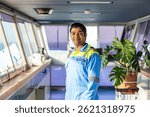 Chief officer on the bridge of a merchant ship, wearing a light blue uniform with epaulettes, working with pride and confidence - an authentic portrait of leadership at sea. Real workplace.
