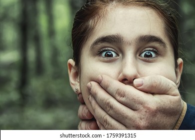 Child Abduction. A Man Puts His Hand Over The Mouth Of A Terrified Teenage Girl. The Concept Of Kidnapping.