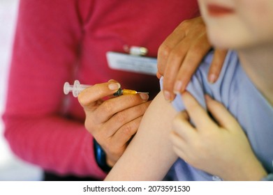 A Child About To Be Given The Combined MMR (mumps, Measles, Rubella) Vaccination Into Their Arm By A Surgery Nurse With A Hypodermic Syringe, England, UK.