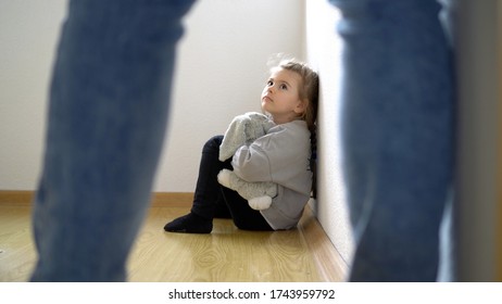 Child abuse concept. Little girl on the floor scared of adult standing. - Shutterstock ID 1743959792