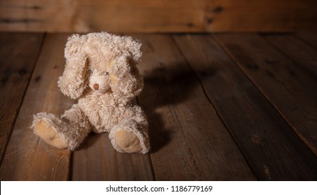 Child abuse concept. Teddy bear covering eyes, dark empty background, copy space