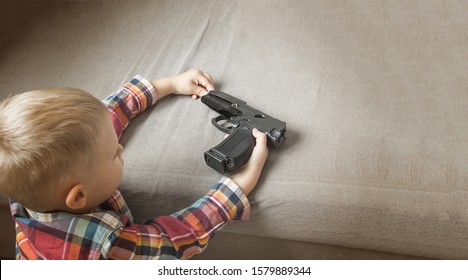 Child Abuse, Dysfunctional Family, Parenting Problems,kid Plays With A Pistol, Firearms. Gun In Children's Hands 