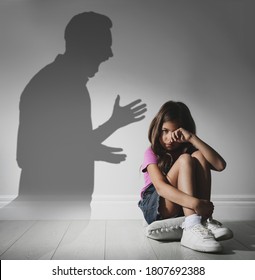 Child abuse. Father yelling at his daughter. Shadow of man on wall