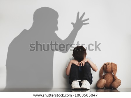 Child abuse. Father yelling at his son. Shadow of man on wall