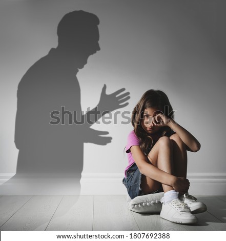 Child abuse. Father yelling at his daughter. Shadow of man on wall