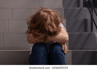 Child abuse. Upset boy sitting on stairs - Powered by Shutterstock