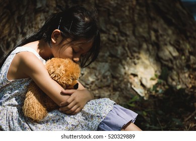 Child Abused, Sad Little Girl Hug Teddy Bear Sitting Anxiety In Park,Children Violence,Family Issues And Abused Concept. 