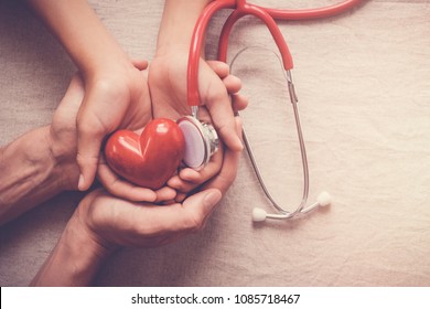 child and adult holding red heart with stethoscope, heart health,  health insurance concept, world health day, world hypertension day