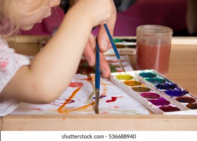 Child With An Adult Painting Brushes And Paints. Hands Only.