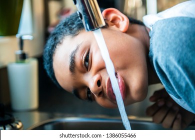 Child Afro American Boy Take Water On His Mouth And Drink In A Kitchen.