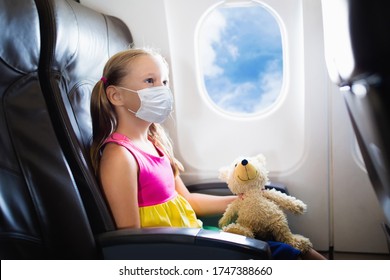 Child In Airplane In Face Mask. Virus Outbreak. Coronavirus And Flu Pandemic. Safe Travel With Young Child And Baby. Kids Flying Airplane In Surgical Masks.