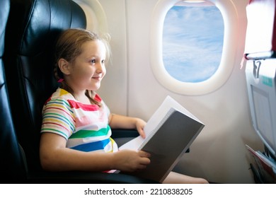 Child In Airplane. Kid With Book In Air Plane Sitting In Window Seat. Flight Entertainment For Kids. Traveling With Young Children. Kids Fly And Travel. Family Vacation. Girl Reading Book In Airplane.