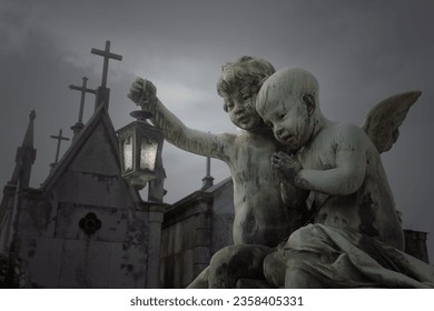 Child angels statue of an old european cemetery with a lamp in the hand at dusk or night