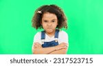 Child, angry and face with arms crossed on green screen with attitude, problem or frustrated in studio. Black kid or girl with mad, grumpy and upset or annoyed facial expression with brat tantrum