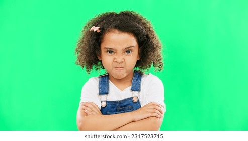 Child, angry and face with arms crossed on green screen with attitude, problem or frustrated in studio. Black kid or girl with mad, grumpy and upset or annoyed facial expression with brat tantrum