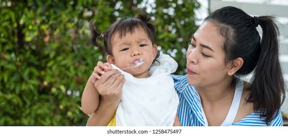 child Anorexia.Mother Feeding Her Baby Girl with a Spoon. Mother Giving Food to her adorable Child at Home