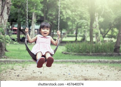 Child Asian Girl Having Fun To Play Swing In Playground In Vintage Color Tone