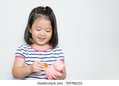 Child asian little girl putting coin into Piggy Bank on white background.family children, money, investments and people concept. - Shutterstock ID 709786210