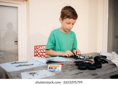 Child assembling a plastic model car, carefully following instructions on a wooden table