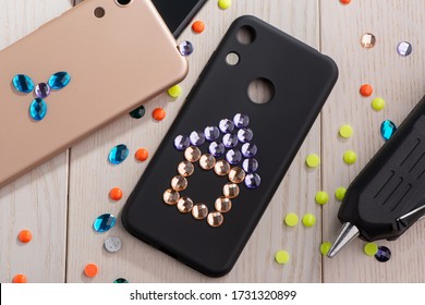 Child Attaching Rhinestones Onto Phone Cases With A Glue Gun. Flower And Home. Cool Art Project For Kids.