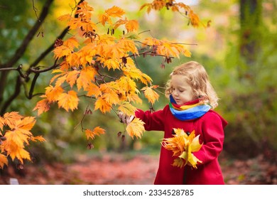 Child in autumn park. Little girl with yellow leaf. Kid playing with fall golden leaves. Kids play outdoors. Children hiking in forest. Toddler kid under a maple tree on a sunny October day. - Powered by Shutterstock