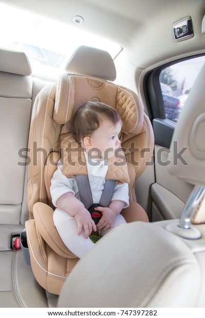 child in a baby car seat.\
Isofix clamping. beige car seat in a bright salon. Protection in\
the car.