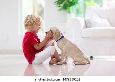 Child With Baby Dog. Kids Play With Puppy. Little Boy And American Cocker Spaniel At Couch. Pet At Home. Animal Care.
