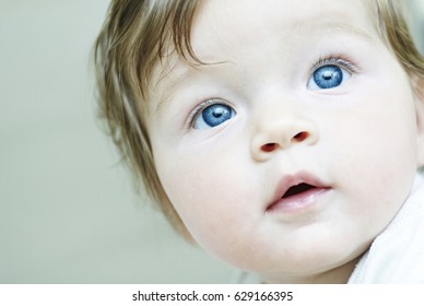 Child Baby Girl With Blue Eyes Looking Up. Close Up Portrait