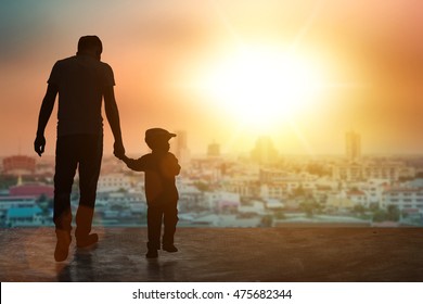 Child, baby holding an adult's hand. Father and son on a walk silhouette background. Children's day.