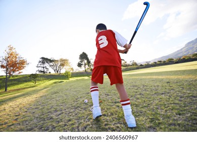 Child, ball and hockey on green grass for game, sports or outdoor practice match in nature. Rear view of young kid or teen player enjoying day on field for fitness, activity or training with blue sky - Powered by Shutterstock