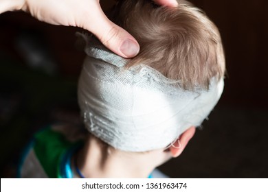 A Child With A Bandaged Head. A Pre-school Boy With A Head Injury. Childhood Trauma. Dissection Of The Scalp In Preschool Children