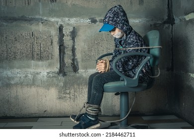 A Child In The Basement Is Sitting On A Chair Tied With A Rope