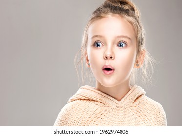 The child is a beautiful girl with wide eyes, look away in surprise. Baby in a knitted sweatshirt . Children's products , clothing and accessories . Expressive facial emotions - Shutterstock ID 1962974806