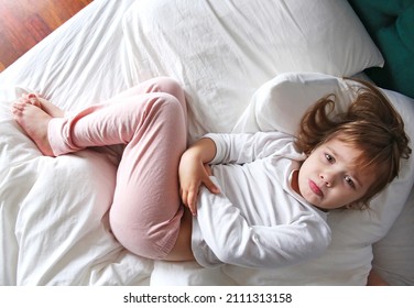 Child in a bed with stomach ache.Caucasian girl with hands on belly. Health disorder concept. Kid has a pain.