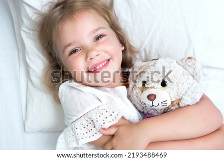 Child in a bed with toy. Caucasian girl portrait. Happy smiling toddler.Kid healthy concept.