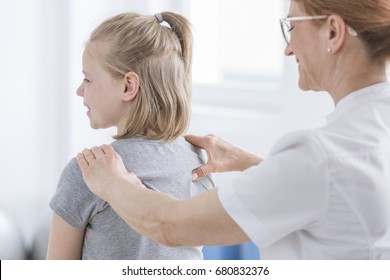 Child being given back massage for pain relief by chiropractor