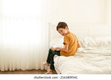 Child Bent Over The Tablet While Sitting On The Bed. The Back Stoops. Concept Of Children Addiction To Gadgets, Back Health, Posture, Childhood, Psychological Health, Little Gamer, Parenthood.