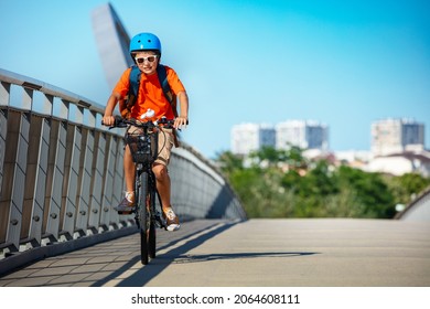 Child In The Bicycle Cycle Over Bridge On Bike Lane With City Buildings On Background, Smiling