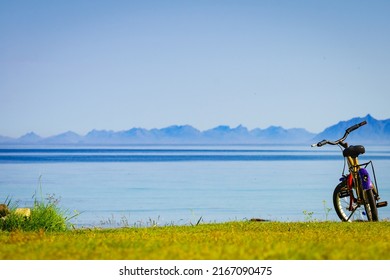 Child bike with safety helmet parked on beach seashore in summer. Lofoten archipelago Norway. Holidays and adventure.